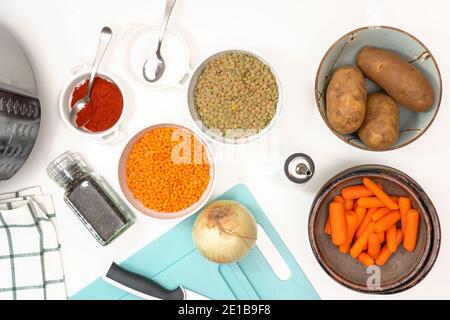 Linsensuppe Zutaten. Rote Linsen, grüne Linsen, Zwiebel, Karotte, Kartoffeln und einige Gewürze auf weißem Hintergrund Stockfoto