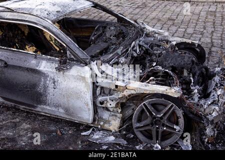 Nahaufnahme des verbrannten Autos, Seitenansicht mit Rad. Auto nach dem Feuer. Brandstiftung. Unfall auf der Straße durch Geschwindigkeitsüberschreitung. Explosion. Stockfoto