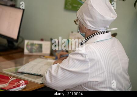 Oberarzt arbeitet mit Papieren mit einem Computer im Vordergrund. Arbeit des Ärzteteams in der Augenarztpraxis. Reife weibliche Arzt schreibt medizinische Stockfoto