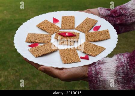 Weibliche Hand hält Winter spezielle süße Gericht von weißem Sesam Und das Zacken schmolzen in Butterschmalz und rollten hinein Bettwäsche garniert und dekoriert w Stockfoto
