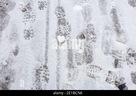 Es gibt viele Fußabdrücke auf der Straße und ein weißes Herz aus Schnee. Gesundes Lifestyle-Konzept, zu Fuß auf Luft. Hochwertige Fotos Stockfoto