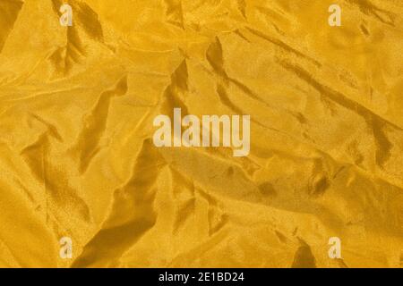 Goldener, zerknitterter Organza-Stoff. Abstrakter Hintergrund. Stockfoto