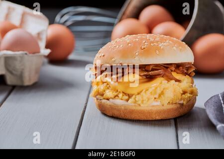 Burger mit gebräuntem Brötchen, karamellisierter Zwiebel, geschmolzenem Käse und Egglut Stockfoto