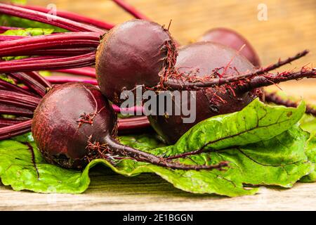 Rote Bete Knollen mit grünen Blättern auf Holztisch. Zubereitung von frischem Salat. Frisches Gemüse für vegetarische Küche. Rüben auf dem Straßenmarkt. Stockfoto
