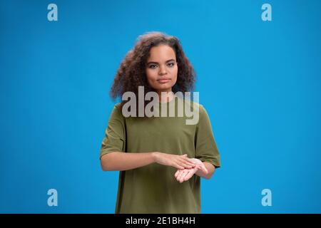 Taube afrikanisch amerikanische Mädchen mit Gebärdensprache zeigt Handgesten. Junge Frau, die in einem olivfarbenen T-Shirt die Kamera positiv anschaut. Isoliert ein Stockfoto