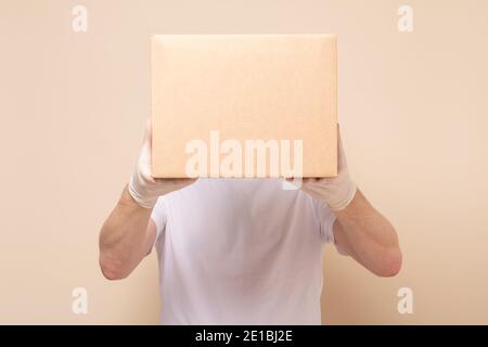 Delivery Mann hält Karton in medizinischen Gummihandschuhen. Online-Shopping und Express-Lieferung . Quarantäne Stockfoto