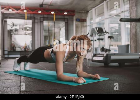 Schöne starke junge Fitness-Frau mit getönten athletischen Körper Planken Übung im Fitnessstudio zu tun. Charmante blonde behaarte weibliche Athlet trainieren an Stockfoto