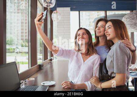 Fröhliche schöne junge Frauen lächeln, Selfies zusammen im Café nehmen, kopieren Raum. Schöne junge Frau nimmt Selfies mit ihren Freunden, Stockfoto