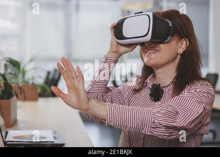 Nahaufnahme einer glücklichen reifen Geschäftsfrau lächelnd, trägt Virtual Reality 3d-Brille, kopieren Raum. Fröhliche Frau mit vr-Headset bei der Arbeit, Platz kopieren. Stockfoto