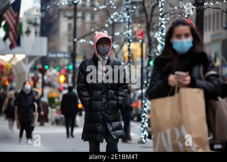 New York, USA. Januar 2021. Menschen, die Gesichtsmasken tragen, gehen entlang der Fifth Avenue in New York, USA, 5. Januar 2021. Die bestätigten COVID-19 Fälle in den Vereinigten Staaten überstiegen am Dienstag 21 Millionen. Quelle: Michael Nagle/Xinhua/Alamy Live News Stockfoto