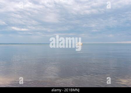 Ein eineinziges weißes Motorkreuzfahrtschiff sitzt auf glasigen Wasser In Port Stephens reflektieren graue Regenwolken darüber Stockfoto