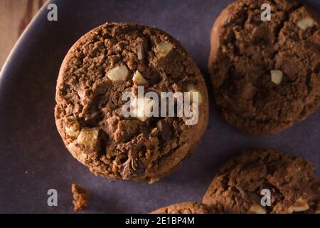 Dreifache Schokolade Chip Cookies mit Stücken von weißer Milch und Dunkle Schokolade mit dunkler kreativer Beleuchtung Stockfoto