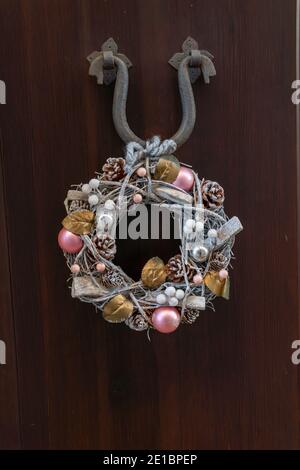 Weihnachtsschmuck auf der Außenseite einer rustikalen Holztür An einer Metallstütze hängen Stockfoto