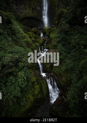 Junger Mann in gelber Jacke vor El Chorro De Giron Wasserfall Kaskade Katarakt bei Cuenca Azuay Ecuador in Südamerika Stockfoto