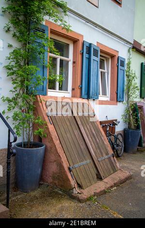 Fassade eines alten Hauses in Neckargemuend, süddeutschland mit blauen Fensterläden und einem großen hölzernen Kellerausgang Stockfoto