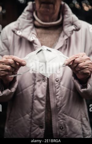 Nahaufnahme der Hände älterer Frauen mit Gesichtsmaske Stockfoto