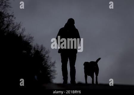 Bremen, Deutschland. Januar 2021. Ein Mann geht mit seinem Hund im Nieselregen über den Osterdeich. Quelle: Sina Schuldt/dpa/Alamy Live News Stockfoto