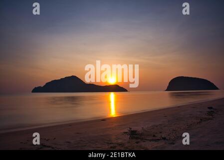 sonnenaufgang hinter dem Berg am Strand mit kolofuler Himmel in Thailand Stockfoto