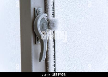 Das Thema des Einfrierens von Haus Kunststoff-Fenster im Haus aufgrund des Alters. Das Konzept der Fensterisolierung vor dem Winter. Stockfoto