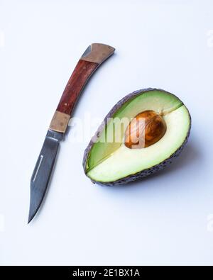 In Scheiben geschnittene Avocado und Messer isoliert auf weißem Hintergrund. Schneiden und öffnen Sie Avocado mit Knickgrube Stockfoto