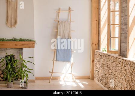 Gemütliches, sonniges Zimmer in hellen Farben mit Holzboden und Wänden, Kamin und Grünpflanzen in Töpfen. Skandinavisches, schlichtes Design. Öko Loft Apartments Stockfoto