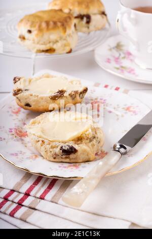 Scones ein klassischer britischer Kuchen gefüllt mit Sultaninen und Rosinen Und wird oft während des Nachmittagstees gebuttert serviert Stockfoto