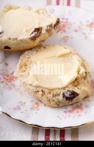 Scones ein klassischer britischer Kuchen gefüllt mit Sultaninen und Rosinen Und wird oft während des Nachmittagstees gebuttert serviert Stockfoto