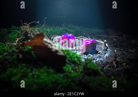 Nahaufnahme rpg-Szene von zwei 10-seitigen Würfel in einem Lichtstrahl, der auf einer Oberfläche von Schmutz und Wurzeln liegt. Stockfoto