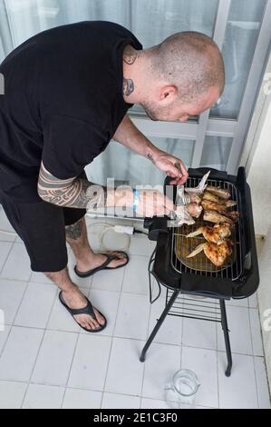 Tätowiert junger Mann bereitet und kleine sehr einfache Grill Stockfoto