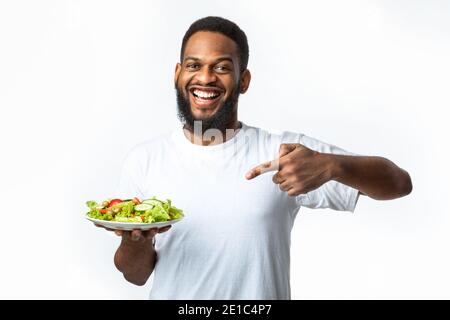 Fröhlich Schwarz Kerl Zeigen Finger Auf Salat Über Weißem Hintergrund Stockfoto