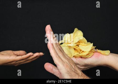 Blur Frau Hand fragen Kartoffelchips aus den Händen des Geizhals. Stock Foto auf schwarzem Hintergrund kopieren Raum Stockfoto