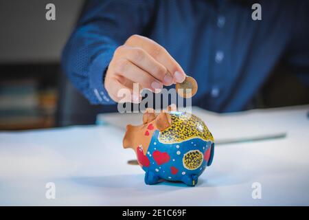 Banker Buchhalter oder Versicherer setzen Geld in ein Sparschwein. Finanzkarte aus Münzen Geschäftskonzept. Opfer des Finanzmarktes. Stockfoto