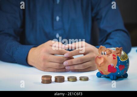 Banker Buchhalter oder Versicherer setzen Geld in ein Sparschwein. Finanzkarte aus Münzen Geschäftskonzept. Opfer des Finanzmarktes. Stockfoto