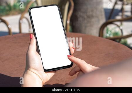 Mockup-Telefon. Zugeschnittenes Bild einer Frau, die ein Smartphone im Straßencafé hält. Frau Texting Mit Ihrem Handy Im Café Stockfoto