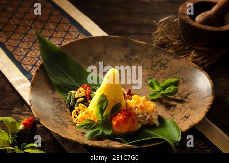 Nasi Kuning. Indonesische festliche Mahlzeit mit Kurkuma-Reis mit Beilagen. Stockfoto