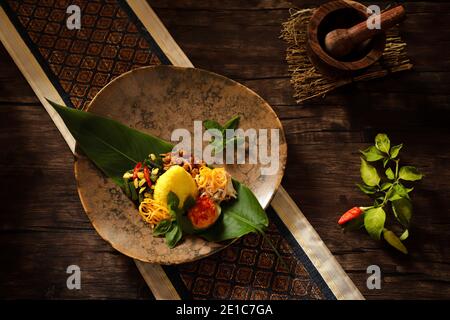 Nasi Kuning. Indonesische festliche Mahlzeit mit Kurkuma-Reis mit Beilagen. Stockfoto