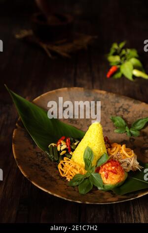 Nasi Kuning. Indonesische festliche Mahlzeit mit Kurkuma-Reis mit Beilagen. Stockfoto