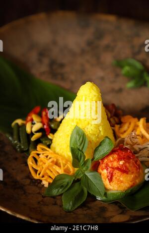 Nasi Kuning. Indonesische festliche Mahlzeit mit Kurkuma-Reis mit Beilagen. Stockfoto