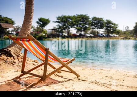 Liegestühle am weißen Sandstrand mit wolkenblauem Himmel und Sonne. Tropisches Urlaubsbanner. Stockfoto