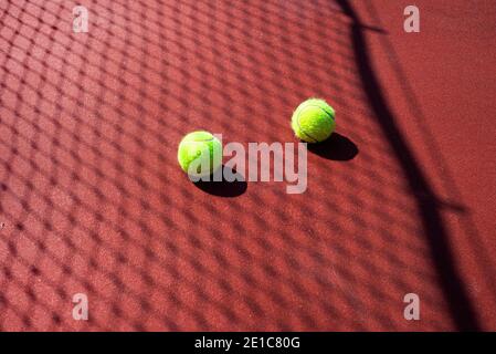 Zwei Tennisbälle auf einem Hartplatz in passierbarer Farbe. Netzschatten. Tennis. Stockfoto
