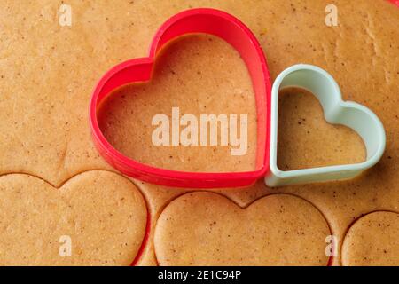 Teig für herzförmige Kekse am Valentinstag. Hausgemachtes Gebäck. Rote und grüne Kunststoff-Backformen. Stockfoto