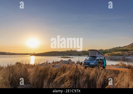 Sonnenaufgang beim Camping mit Offroad Camper VW T4 Syncro California Reisebus-Campervan mit Pop-up-Dach am Lake Alto Rabagão Dam - nördlich von Portugal Stockfoto