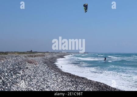 Ein Kiteboarder wird von einem Powerdrachen nahe der Küste am schönen blauen Himmel über Wasser gezogen. Der Mensch nutzte die Kraft des Windes. Extremsport. Zypern Europa. Stockfoto