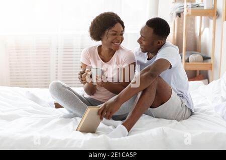 Schwarzes Paar in der Liebe sitzt auf dem Bett und spricht Stockfoto