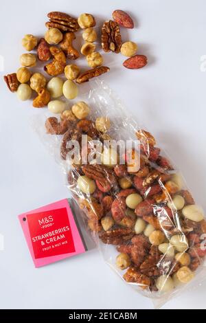Packung mit M&S Erdbeeren & Sahne Obst & Nuss Mix Geöffnet mit verschüttetem Inhalt, der isoliert auf weißem Hintergrund verschüttet wurde Stockfoto