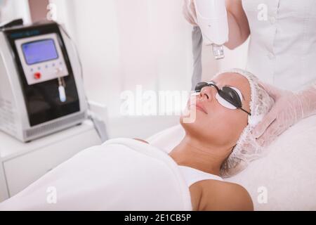 Reife Frau bekommen Gesichtslaser Behandlung. Professioneller Dermatologe, der Hautpigmentierung bei einer weiblichen Patientin entfernt Stockfoto