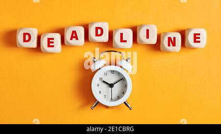 Das Wort Deadline auf Holzwürfel mit Wecker. Geschäfts-, Job- oder Projektterminkonzept. Stockfoto