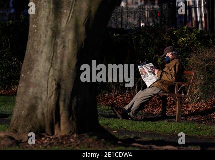 Loughborough, Leicestershire, Großbritannien. Januar 2021. Ein Mann liest eine Zeitung im Southfields Park während der dritten nationalen Covid-19-Sperre. Credit Darren Staples/Alamy Live News. Stockfoto