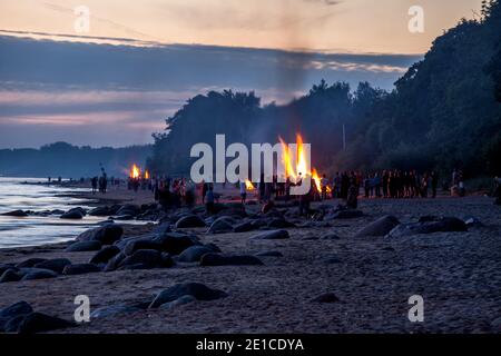 Nicht erkennbare Menschen feiern Sommersonnenwende mit Lagerfeuer am Strand Stockfoto