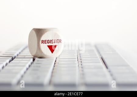 Das Wort Register mit Pfeil-Symbol auf Holzwürfel mit Computer-Tastatur. Online-Registrierungskonzept. Stockfoto